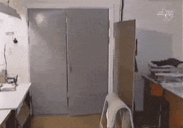 a room with a table , chairs , a blender and a gray door .