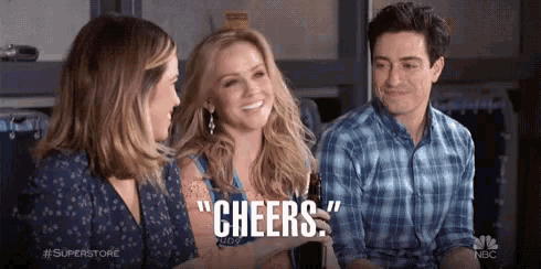 a man and two women are sitting next to each other and a man is holding a beer .