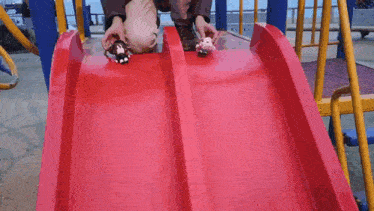 a person is going down a red slide with a toy on it