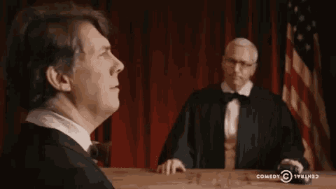 a man in a tuxedo stands in front of a judge with a comedy central logo in the corner