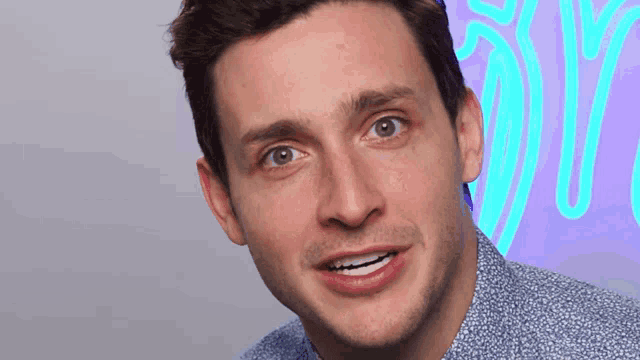 a close up of a man 's face with a neon sign behind him that says 50