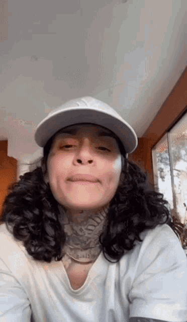 a woman with long curly hair wearing a white hat and a white shirt