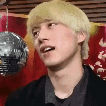 a close up of a man 's face with a disco ball behind him