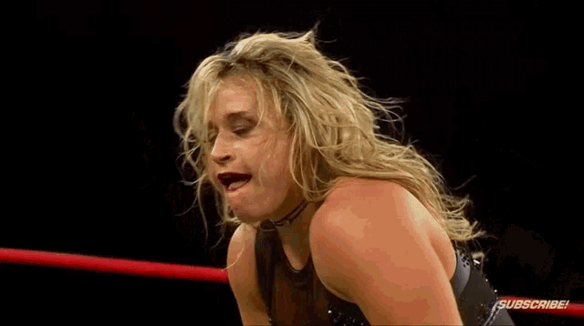 a woman is kneeling down in a wrestling ring and making a face .