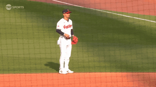 a baseball player wearing a guardians jersey stands on the field