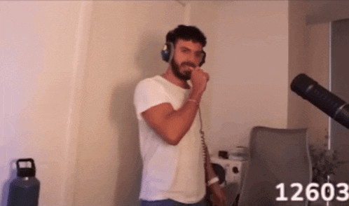 a man wearing headphones is singing into a microphone with the number 12603 on the bottom right