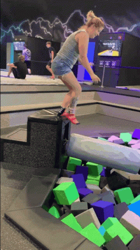a woman is doing a trick on a trampoline in a gym