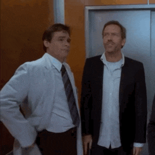 two men standing next to each other in front of an elevator door