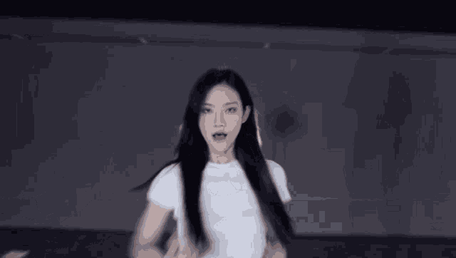 a young woman in a white crop top is dancing in a dark room .