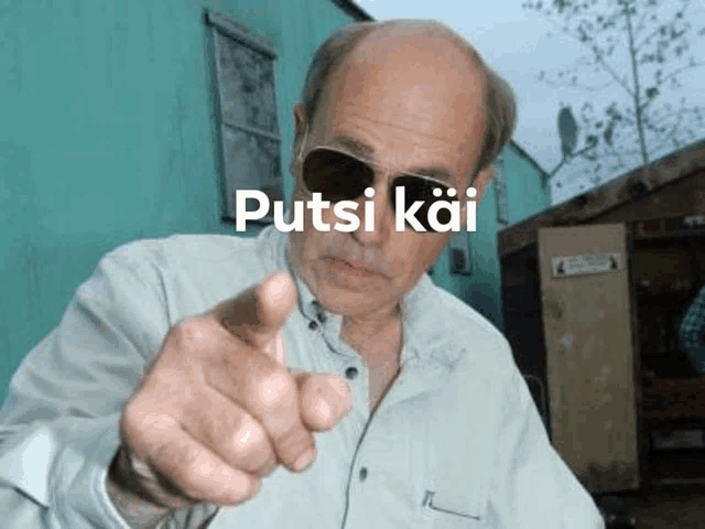 a bald man wearing sunglasses is pointing at the camera with the word putsi kai written on the bottom