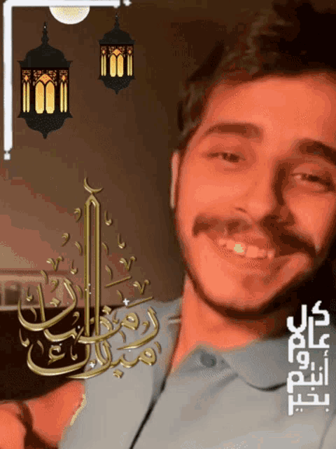 a man with a beard and mustache is smiling in front of a lantern with arabic writing on it