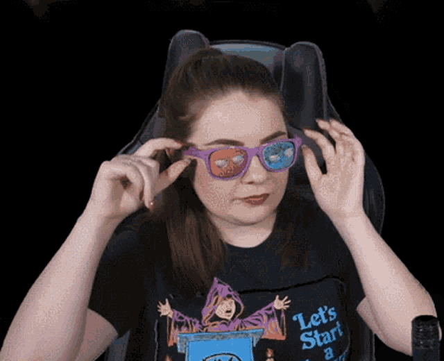a woman wearing 3d glasses and a black shirt that says let 's start