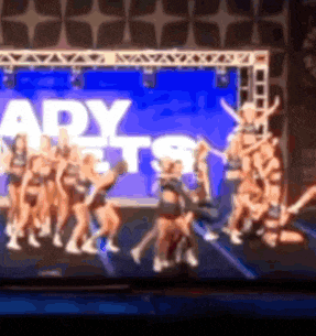 a group of cheerleaders are performing on stage in front of a sign that says ady