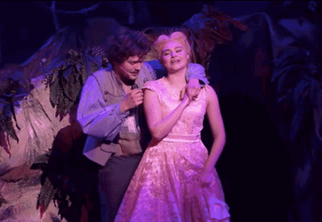 a man and a woman are on a stage with purple lights behind them