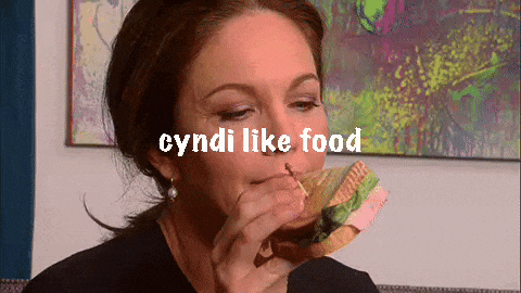 a woman is eating a sandwich with the words cyndi like food written above her