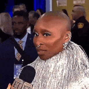 a woman with a nose ring is talking into a microphone while wearing a fur coat .