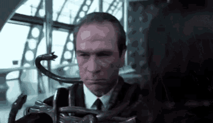 a man in a suit and tie is holding a snake around his neck in a room .