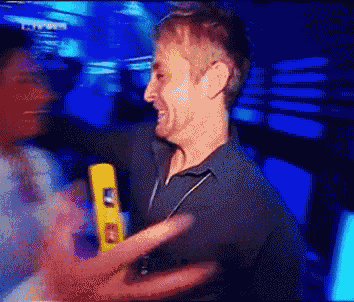 a man in a black shirt is holding a yellow object that says ' a ' on it .