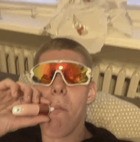 a man wearing sunglasses is taking a pill from a bottle .