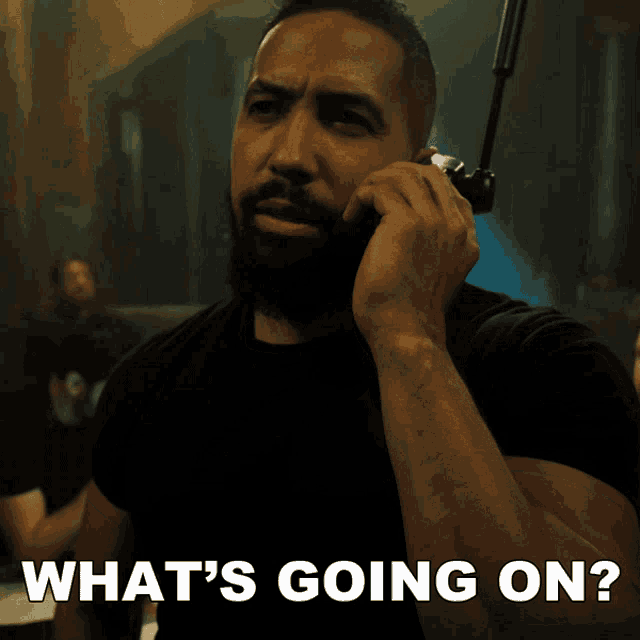 a man with a beard talking on a walkie talkie with the words what 's going on below him