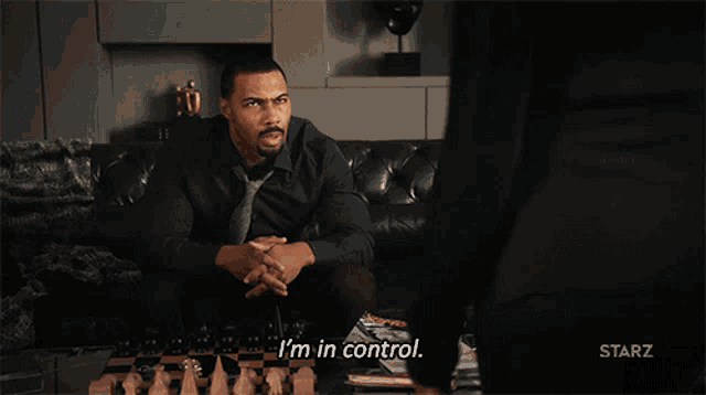 a man sitting on a couch playing a game of chess and says i 'm in control