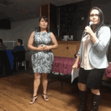 two women are standing next to each other one is holding a microphone