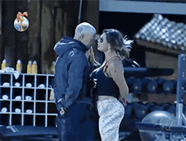 a man and a woman are kissing in front of a shelf with bottles