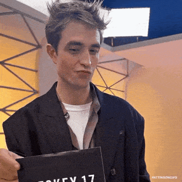 a man in a suit is holding a piece of paper that says ' key 17 ' on it