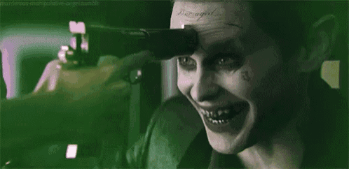 the joker is pointing a gun at someone 's face .