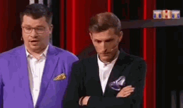 two men in suits are standing next to each other on a stage .