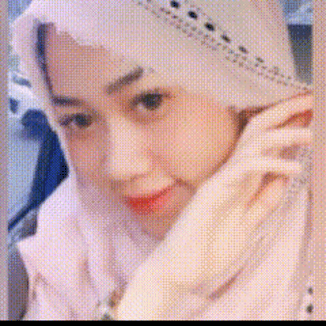 a woman wearing a white hijab and a white jacket is talking on a cell phone .