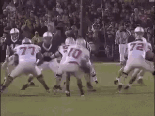 a group of football players are playing a game on a field with a referee .