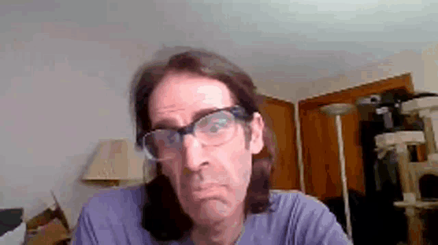 a man wearing glasses and a purple shirt makes a funny face