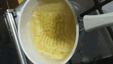 noodles are being cooked in a pot on a stove