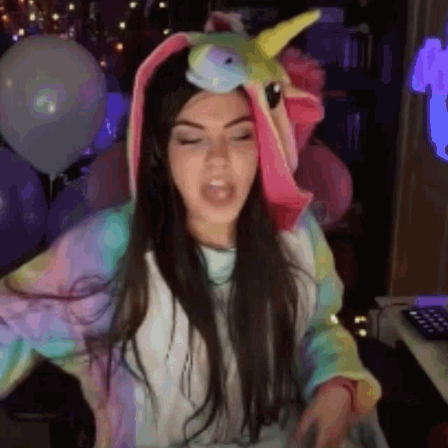 a woman wearing a unicorn costume is standing in front of balloons and a keyboard .