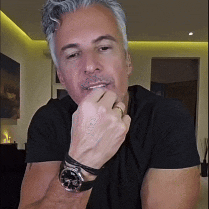 a man wearing a black shirt and a watch has his hand on his mouth