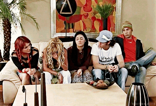 a group of people are sitting on a couch and one of them is wearing a t-shirt that says ' rock '