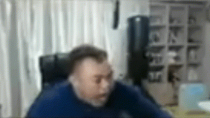 a man in a blue shirt is sitting in a chair in front of a computer monitor .