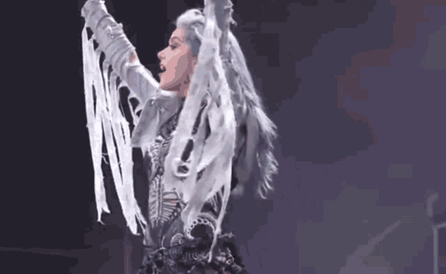 a woman with blue hair and white clothes is dancing on a stage .