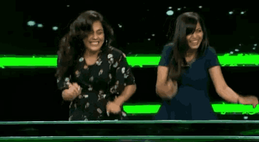 two women are dancing on a green screen .