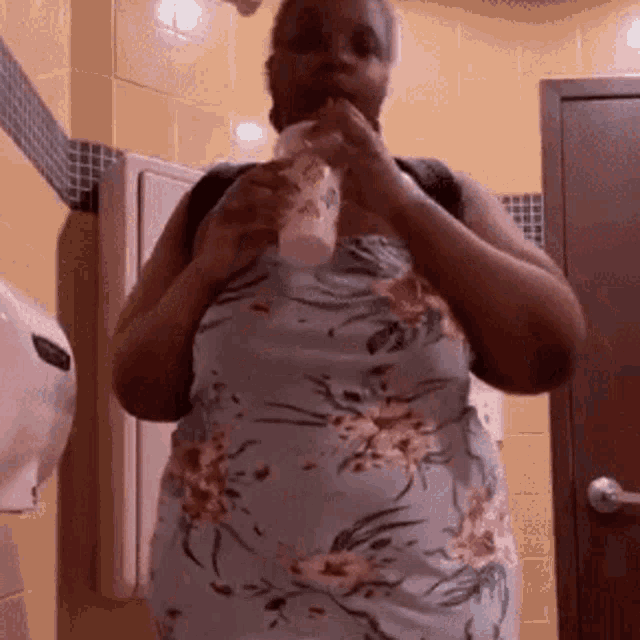 a woman in a floral dress is drinking from a cup