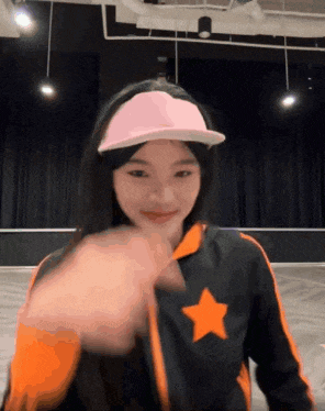 a girl wearing a pink hat and a black jacket with an orange star