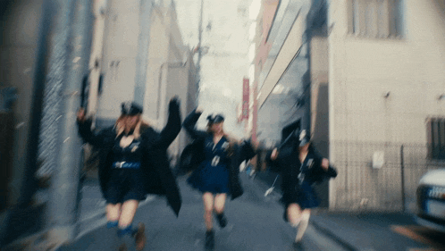 a blurred image of a group of girls running down a street