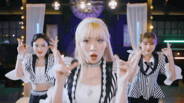 a group of girls are dancing in a room with a disco ball behind them