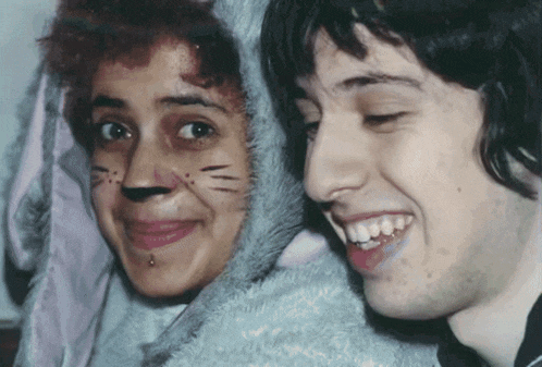 a man and a woman with cat face paint are smiling