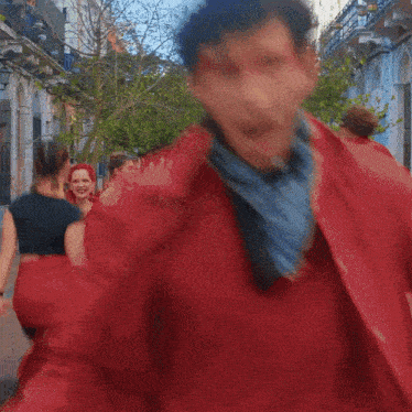 a group of people are walking down a street and one of them has red paint on his face