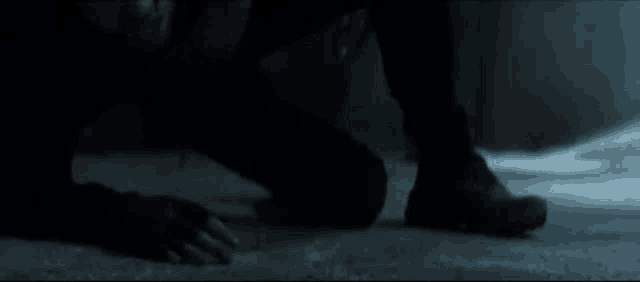 a person is kneeling on the ground with blood coming out of their feet .