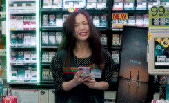 a woman standing in front of a display of cigarettes with a sign that says new brand