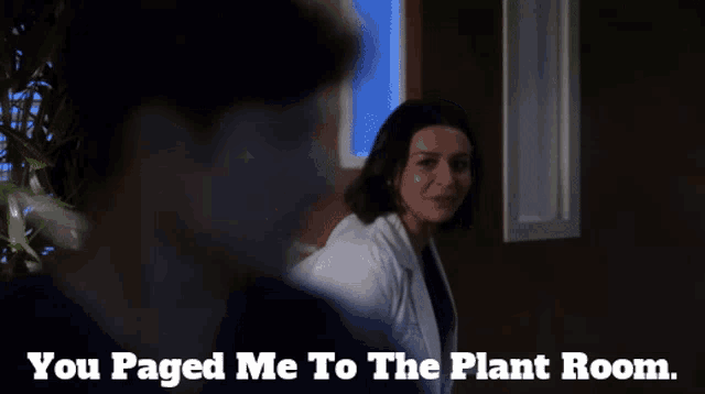 a woman in a lab coat is talking to a man in a dark room with the words you paged me to the plant room below her