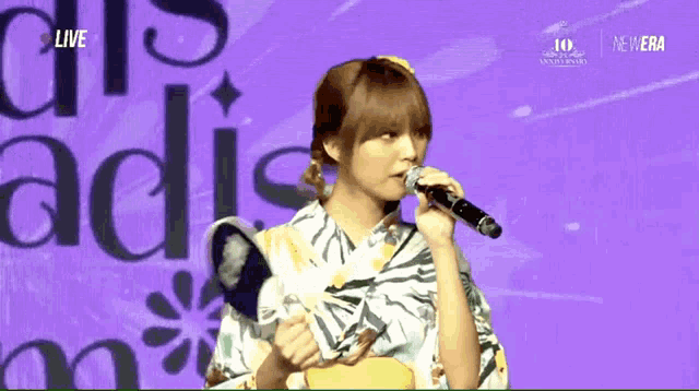 a woman in a kimono singing into a microphone with the words live on the bottom